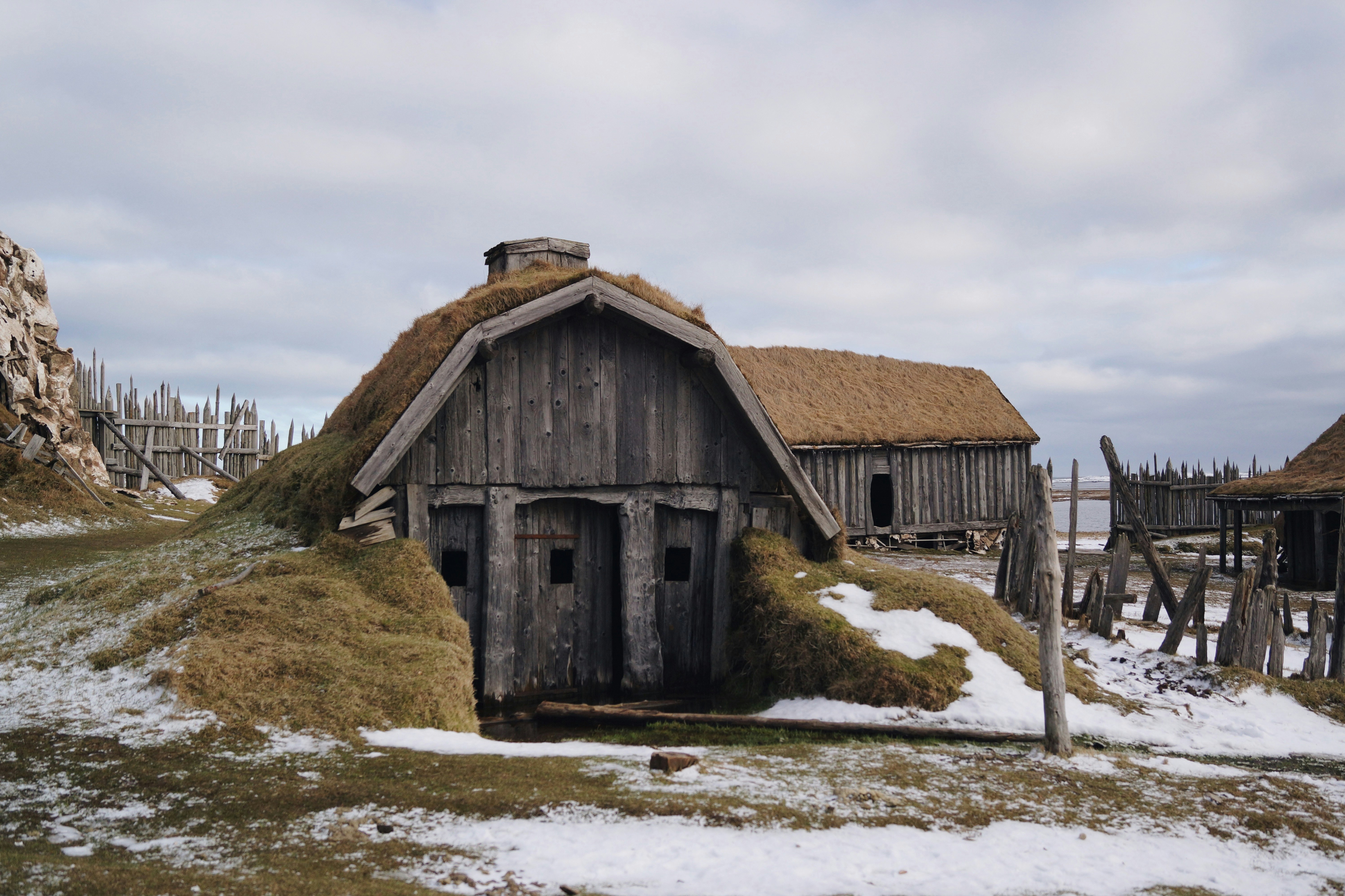 gray wooden house near sea under white skies